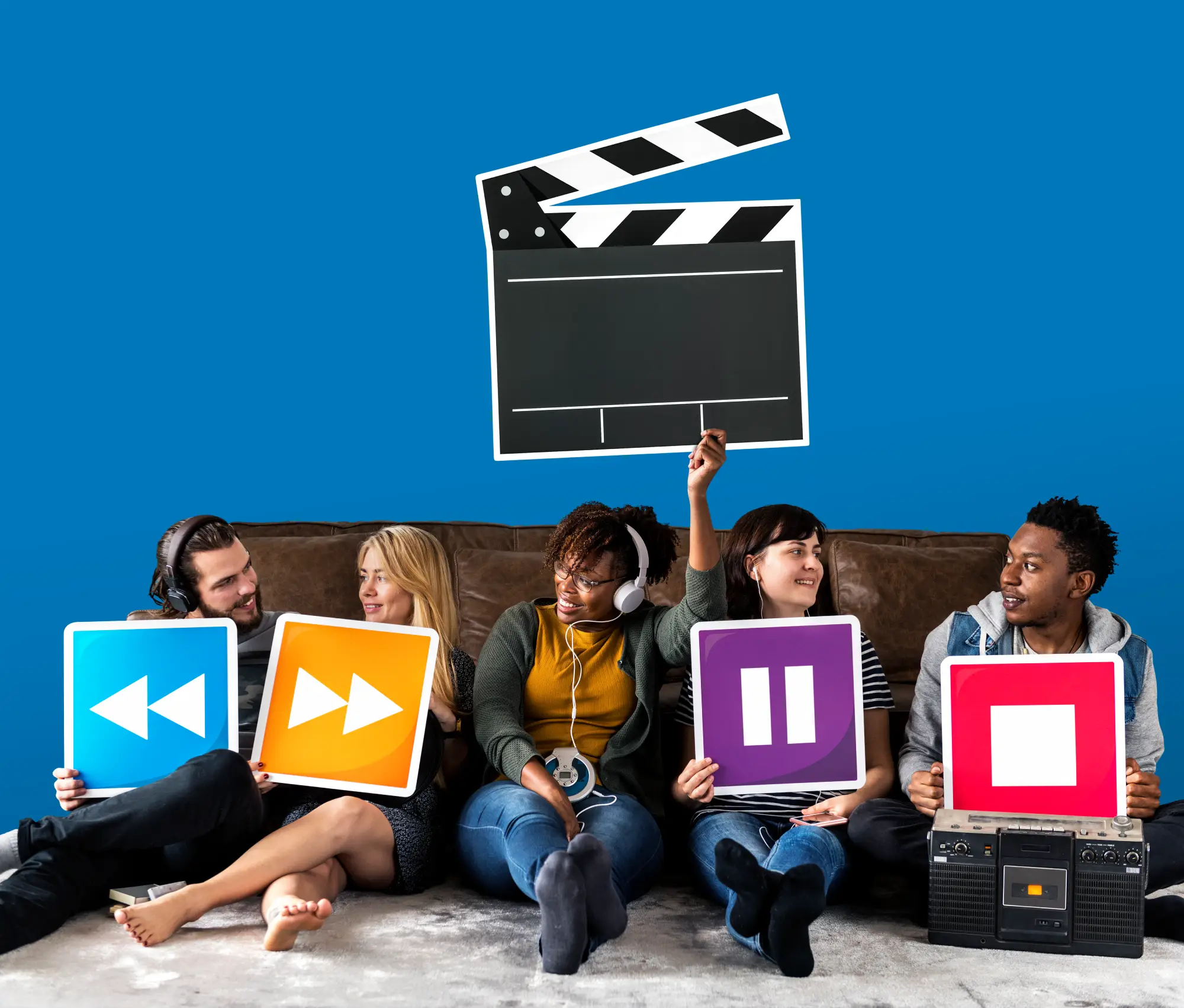 Group of friends sitting on couch holding colorful media control icons with movie clapperboard on blue background, representing video production and streaming