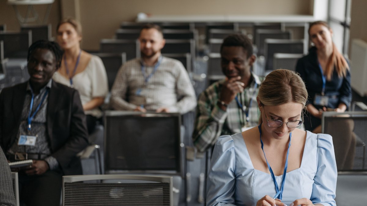 Participants sitting in a seminar room using smartphones and gadgets during a business presentation